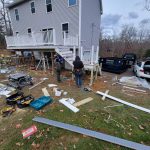 Construction workers installing a deck with a Reed's dumpster on site