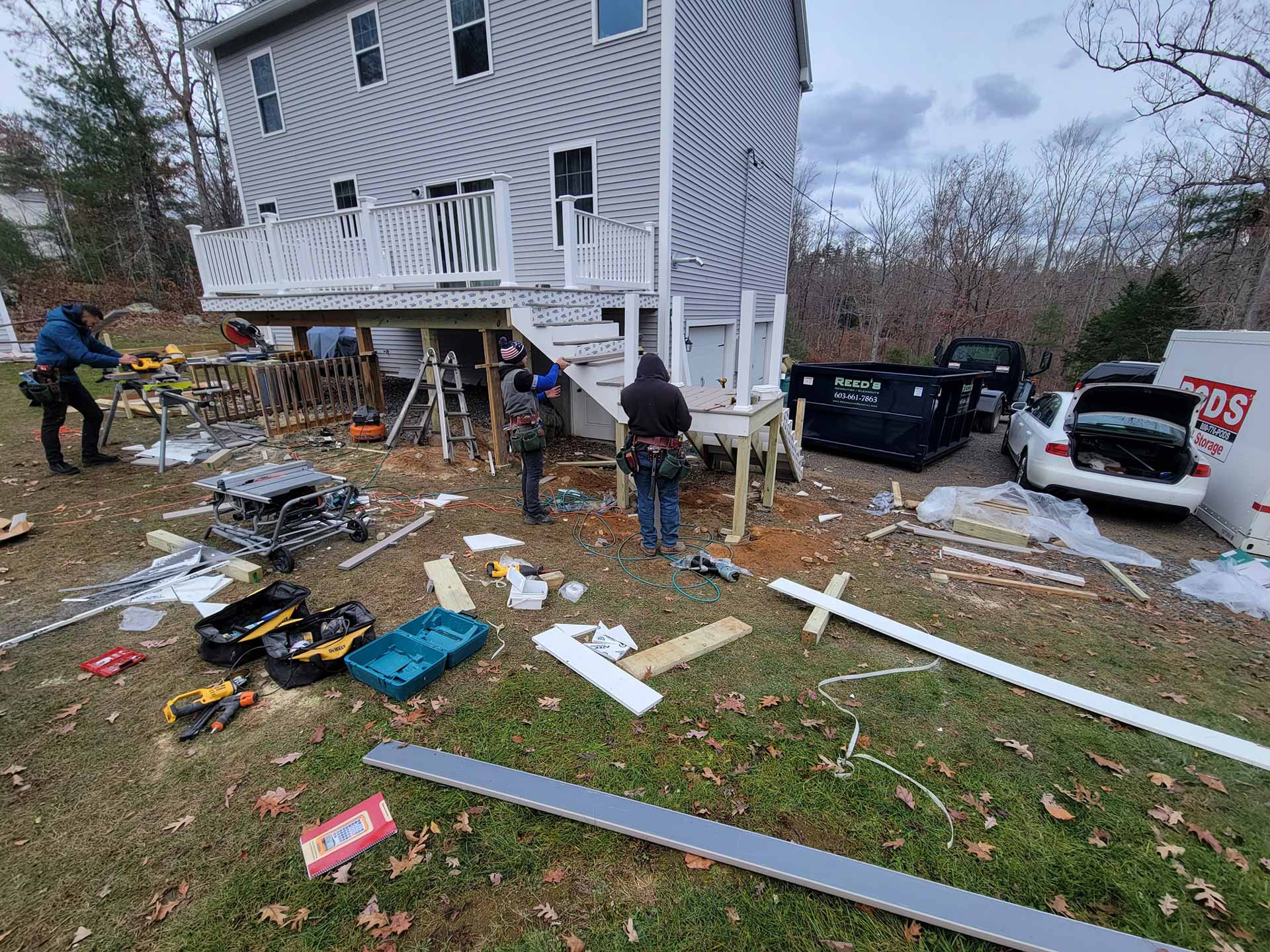 Construction workers installing a deck with a Reed's dumpster on site