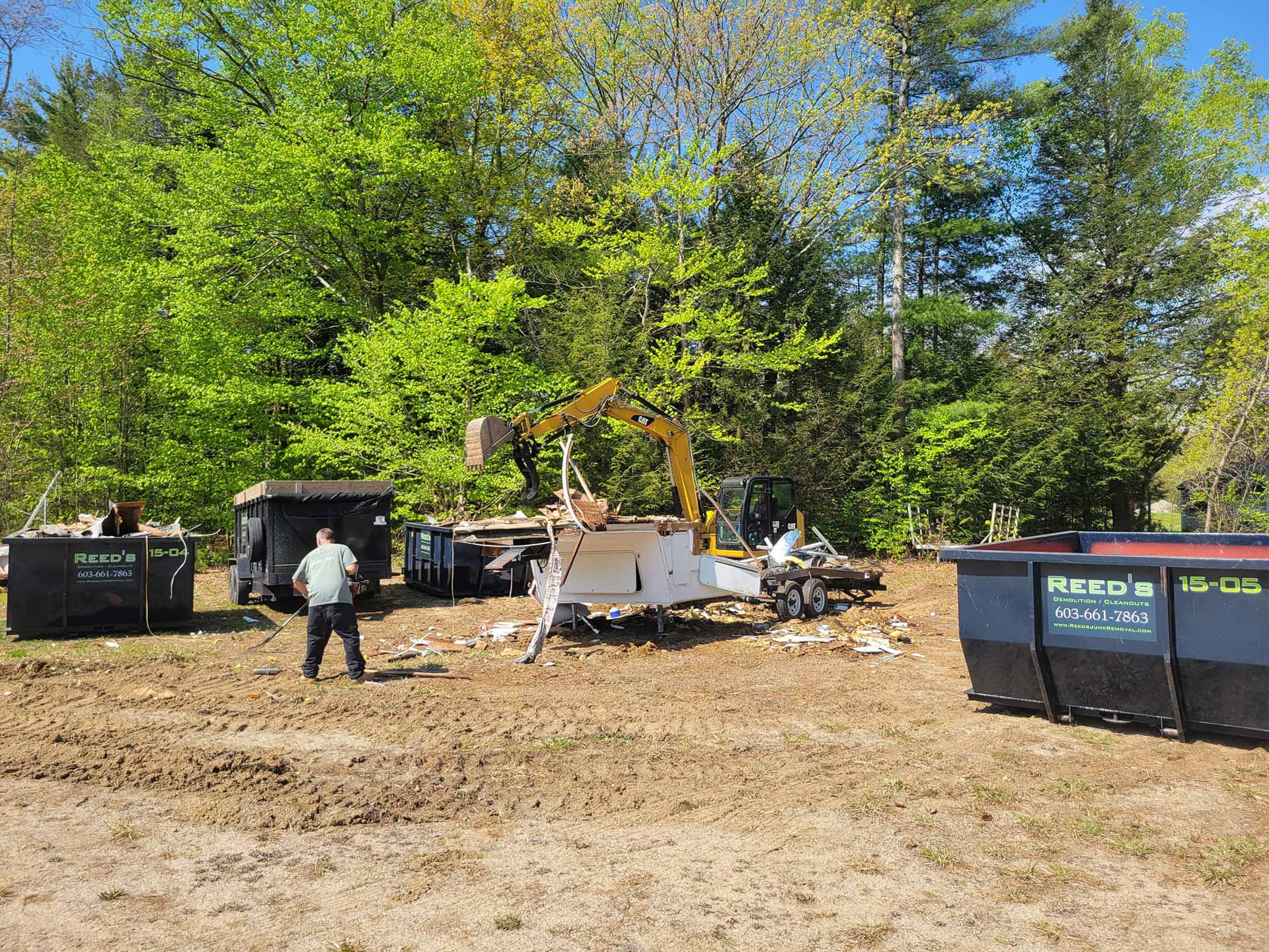 Multiple dumpsters on a lot where a camper is being destroyed