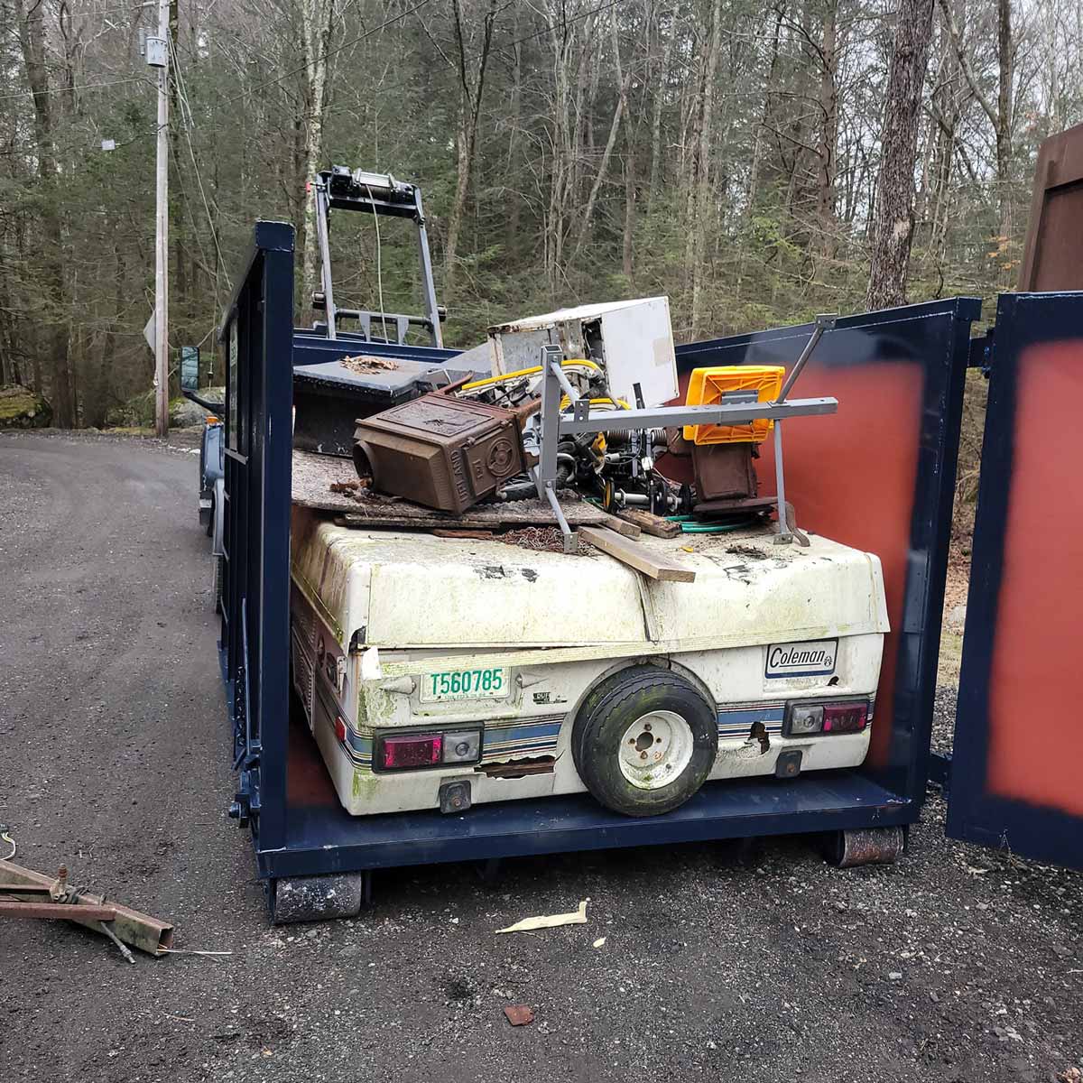Reed dumpster with parts of an old camper in it
