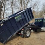 Reed's Demolition & Cleanouts LLC truck dropping off a dumpster
